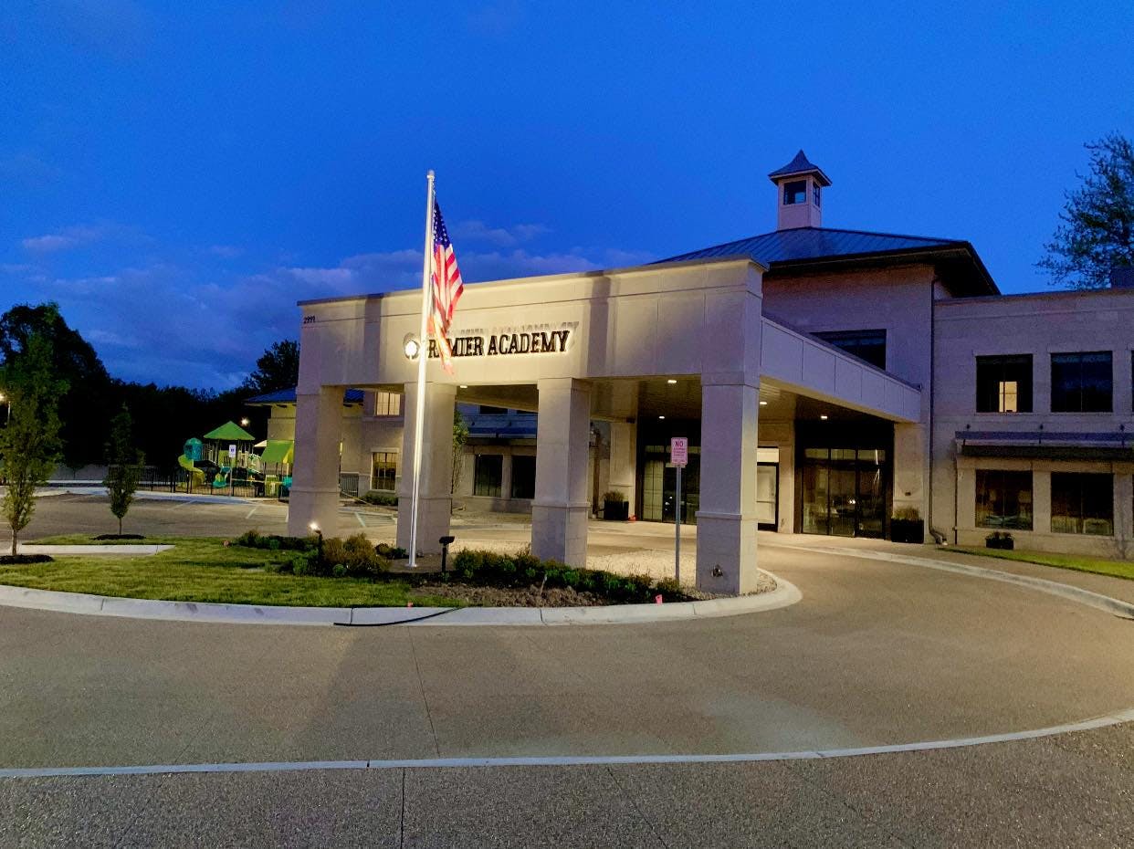 Building with a sign that reads "RIVER ACADEMY" and an American flag
