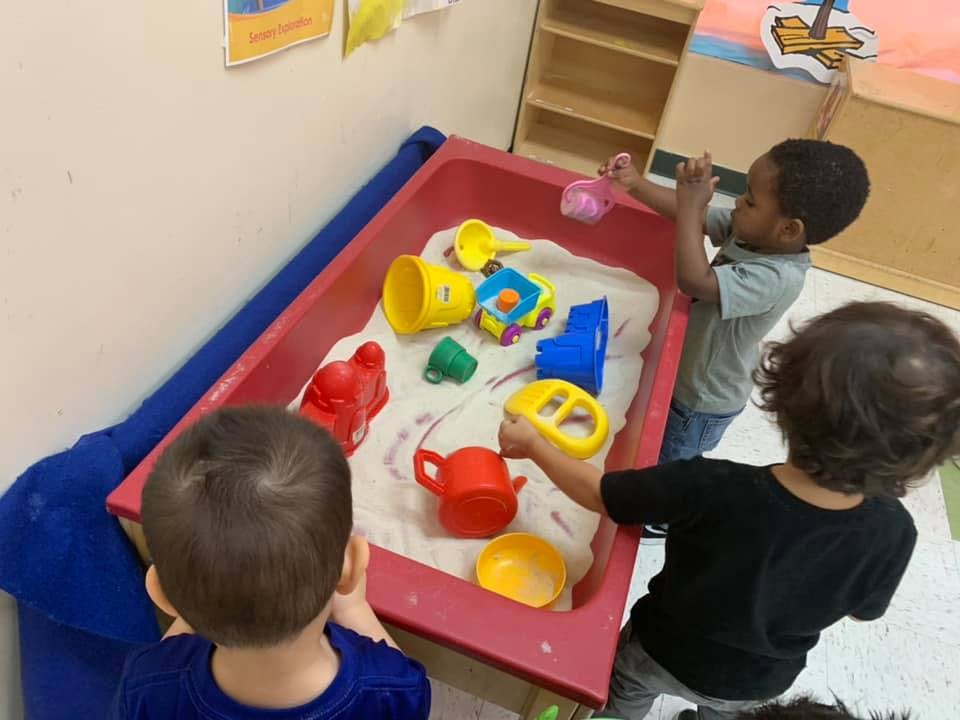 Children playing with toys in a sand table