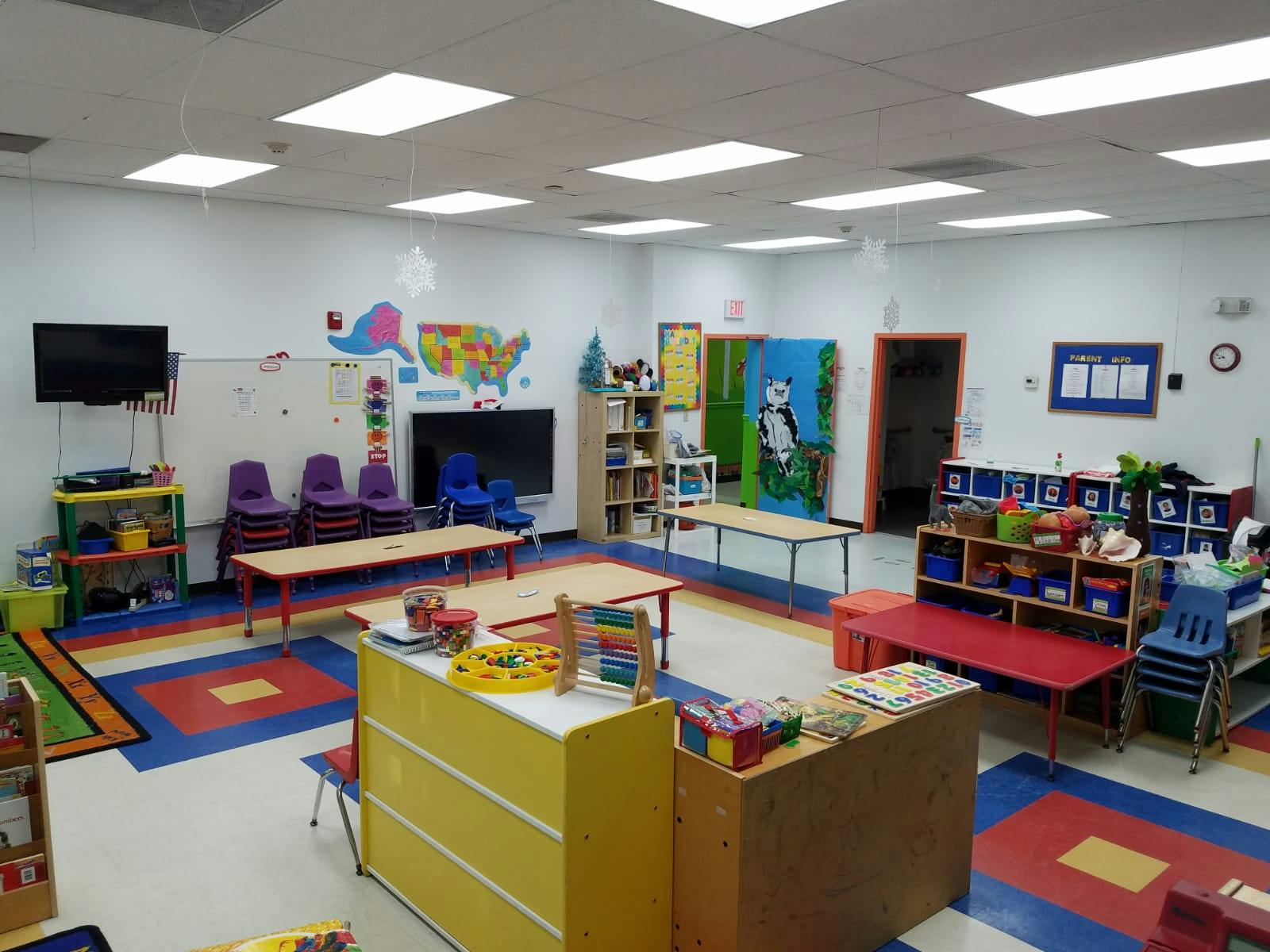 Empty classroom with colorful rugs, small tables, and chairs