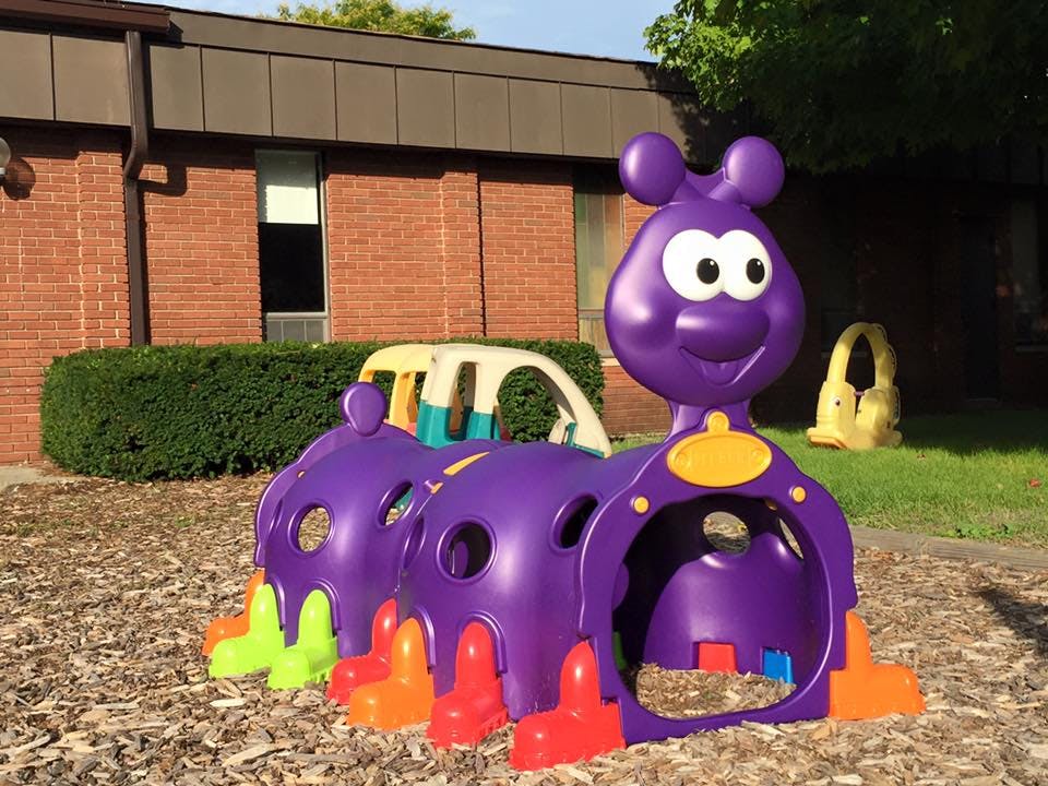 Purple caterpillar-shaped playground tunnel on wood chips
