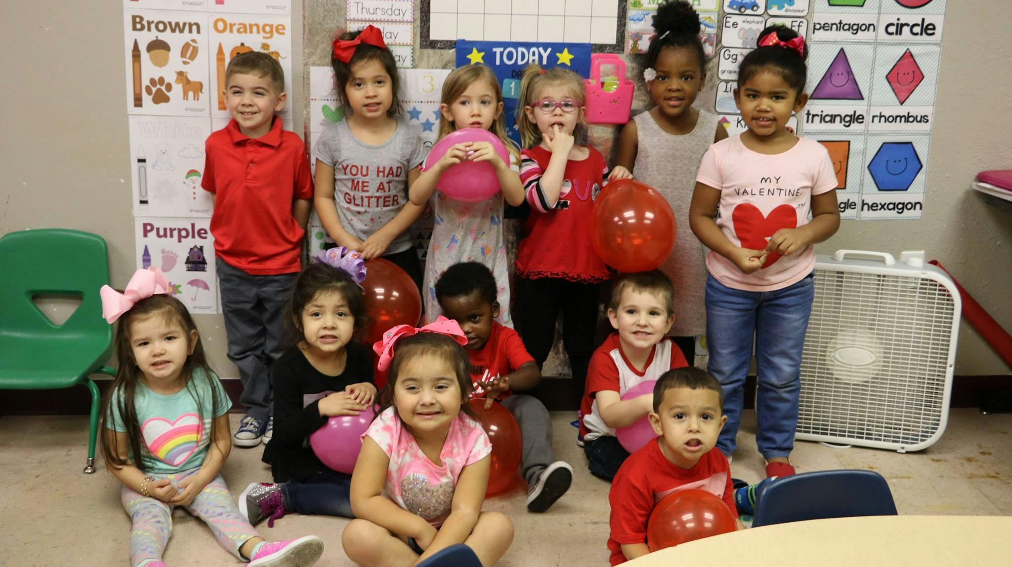 Group of children in a classroom holding balloons