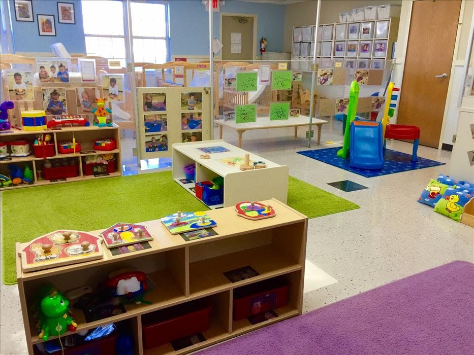 Classroom filled with toys, child-sized furniture, and colorful rugs