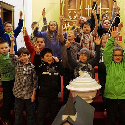 Group of children holding up yellow palm fronds