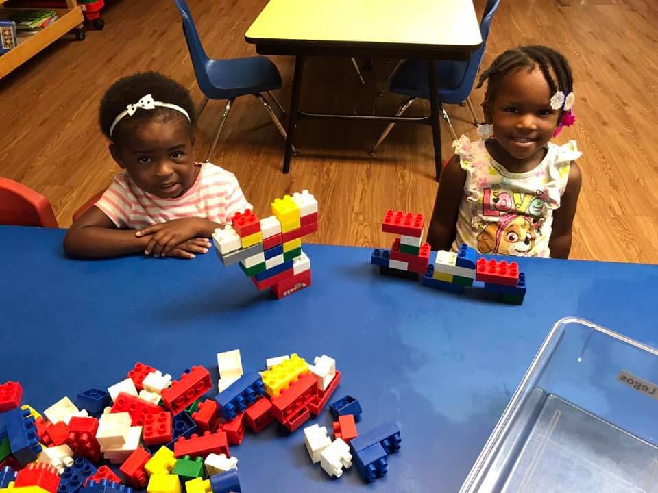 Two children playing with colorful building blocks at a blue table
