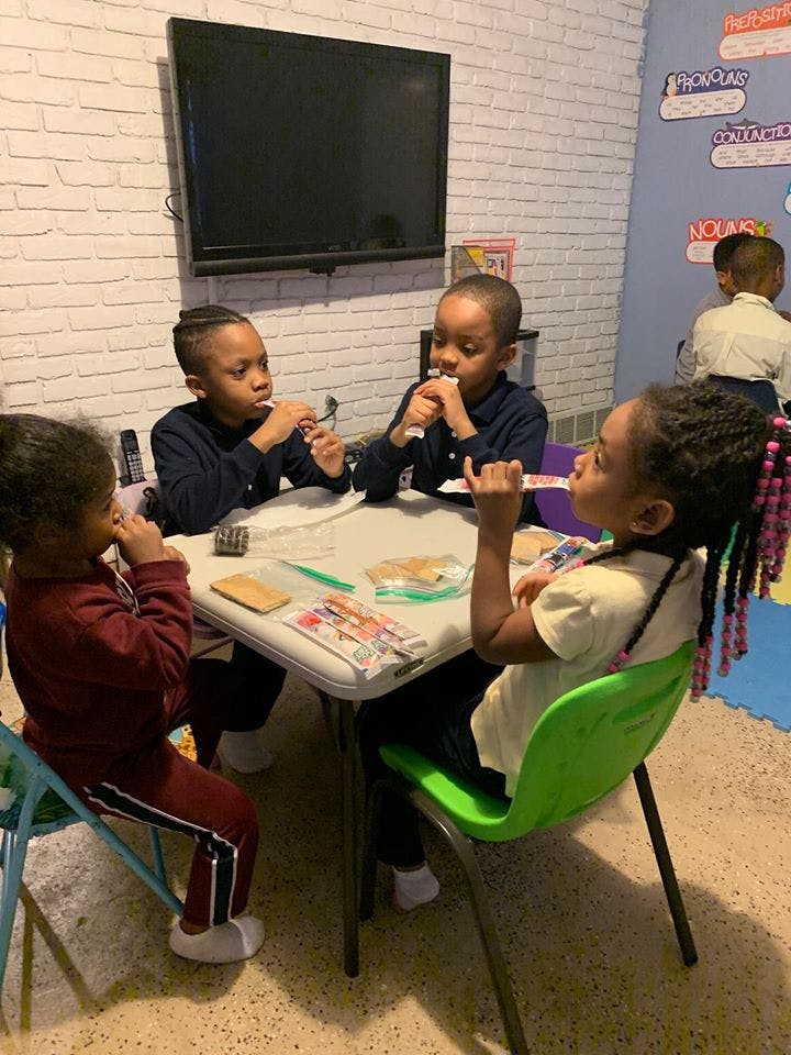 Four children sitting at a table eating snacks
