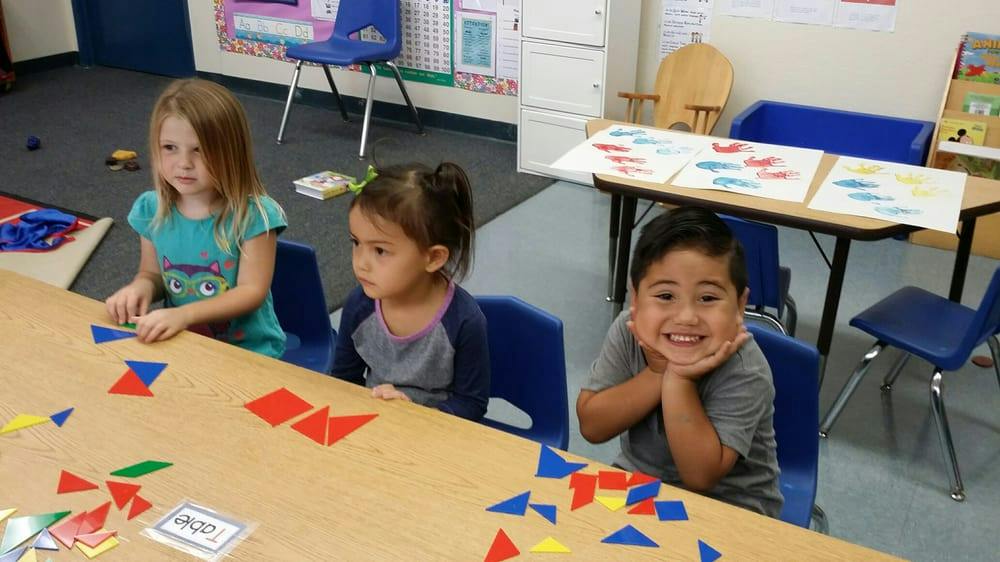 Three children at a table with colorful geometric shapes