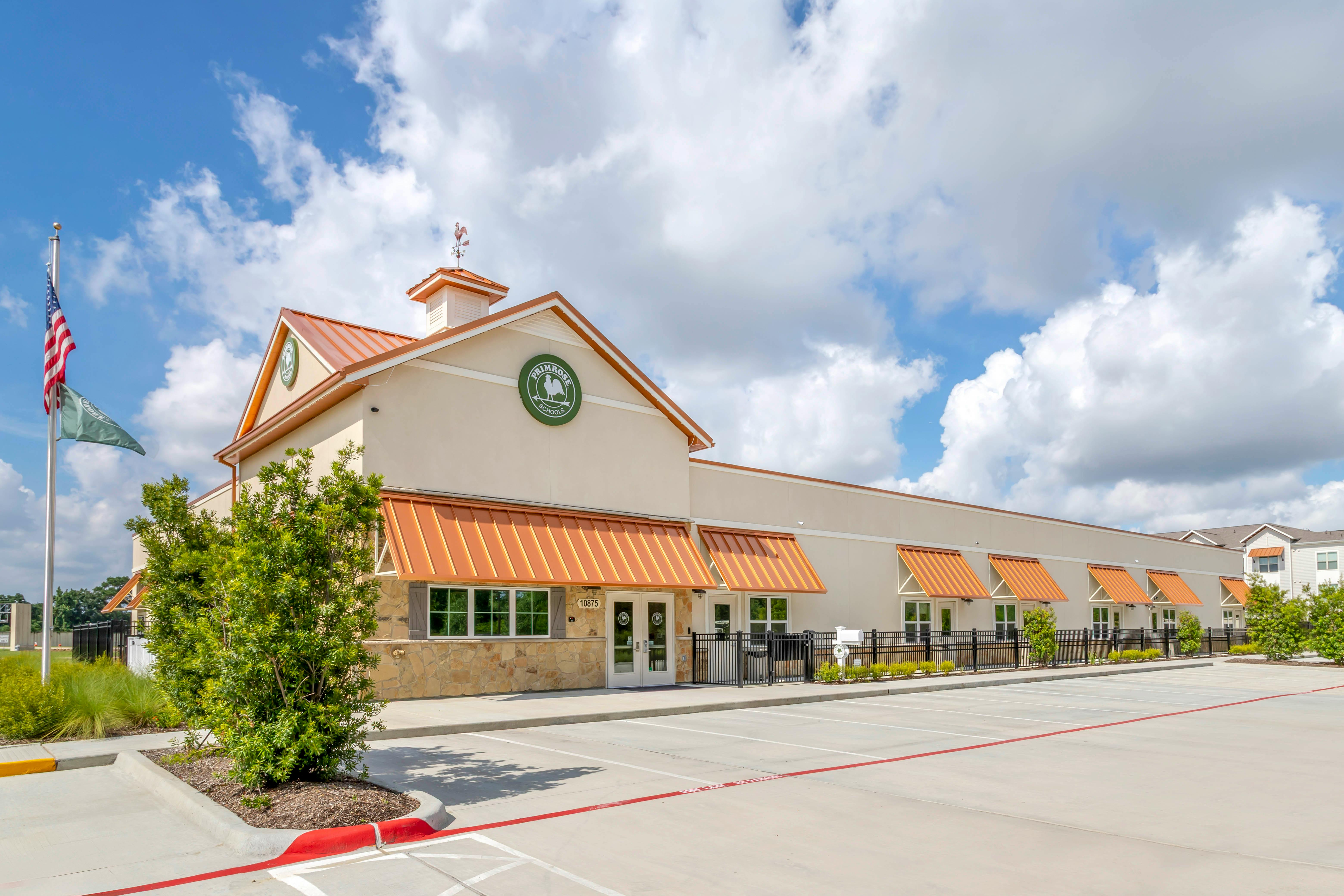 Primrose Schools building with orange awnings and an American flag flying