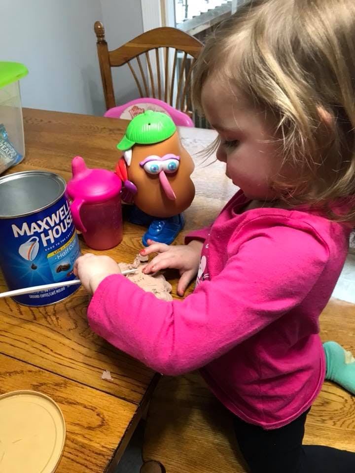 Child playing with a toy and modeling clay on a wooden table