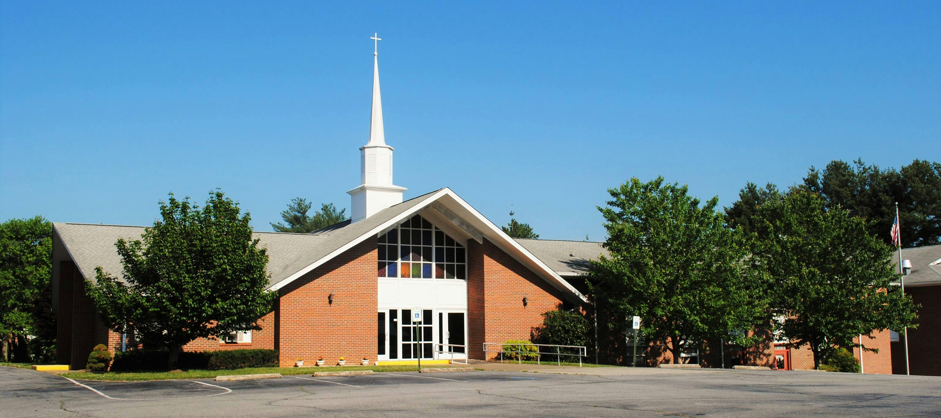 Brick church building with a white steeple and large windows