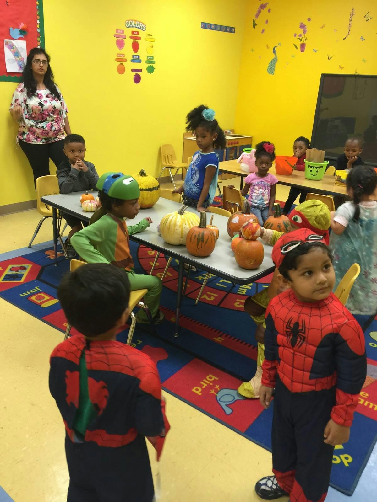 Adult and children in a classroom with pumpkins on a table