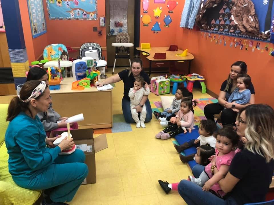 Adults and children sitting on the floor in a classroom