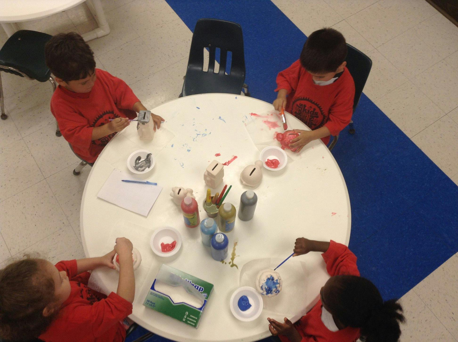Children painting at a table in a classroom