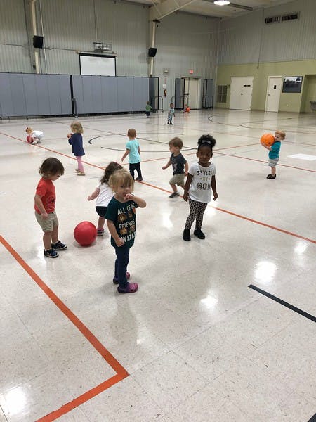Multiple children playing with balls in a gymnasium