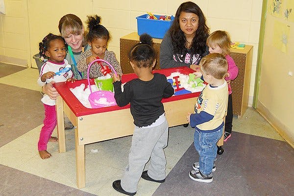 Adults and children gathered around a sensory table