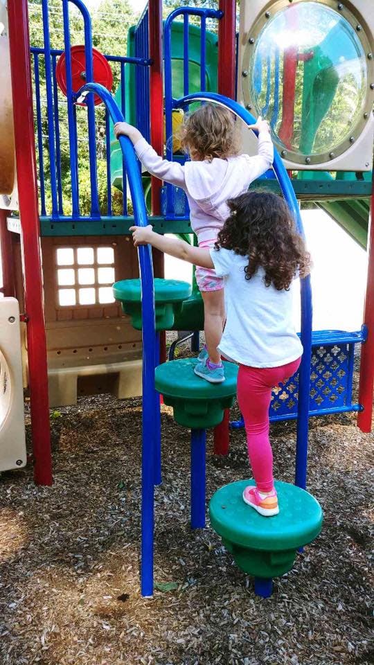 Two children climbing on playground equipment