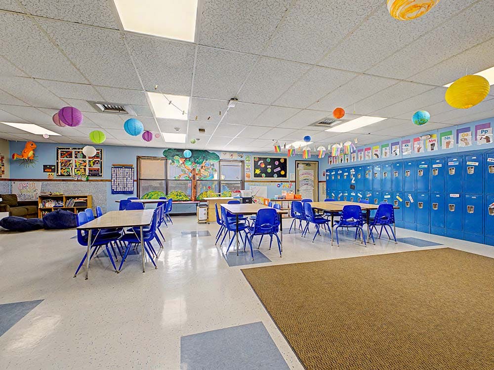 Empty classroom with blue lockers, tables, and chairs