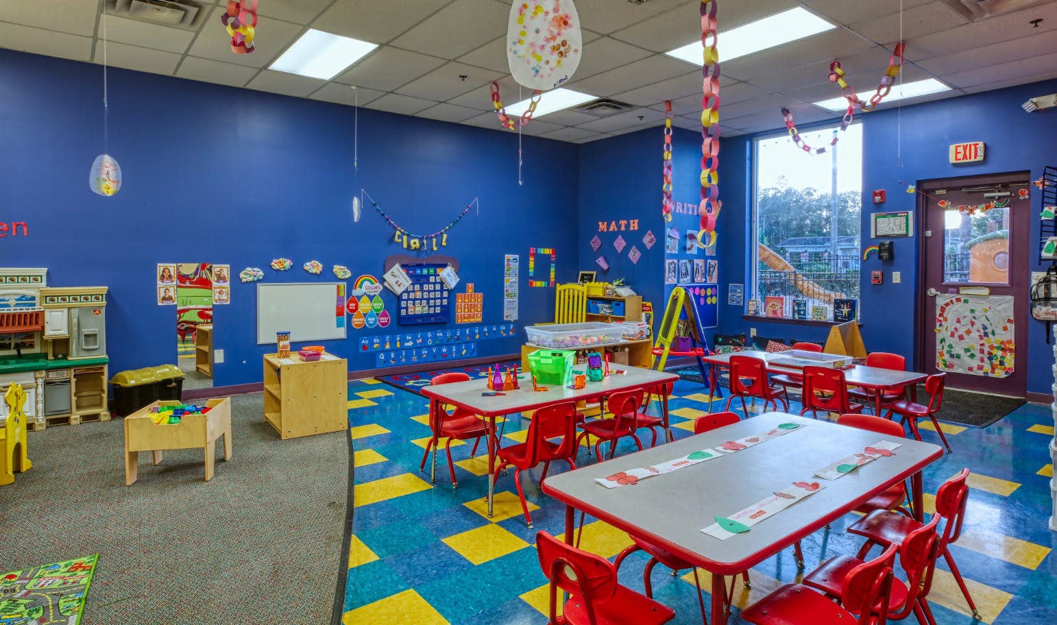 A colorful classroom with blue walls, red tables, and yellow and blue checkered floor