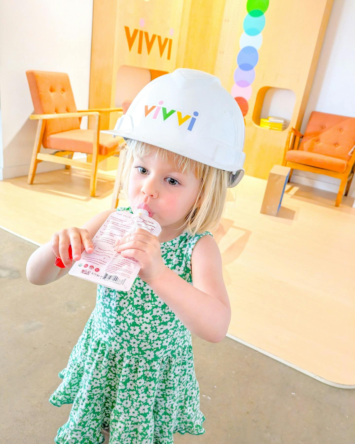 Child in a hard hat drinking from a pouch