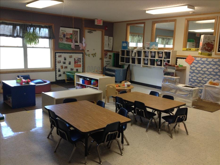 A classroom with tables, chairs, and learning materials