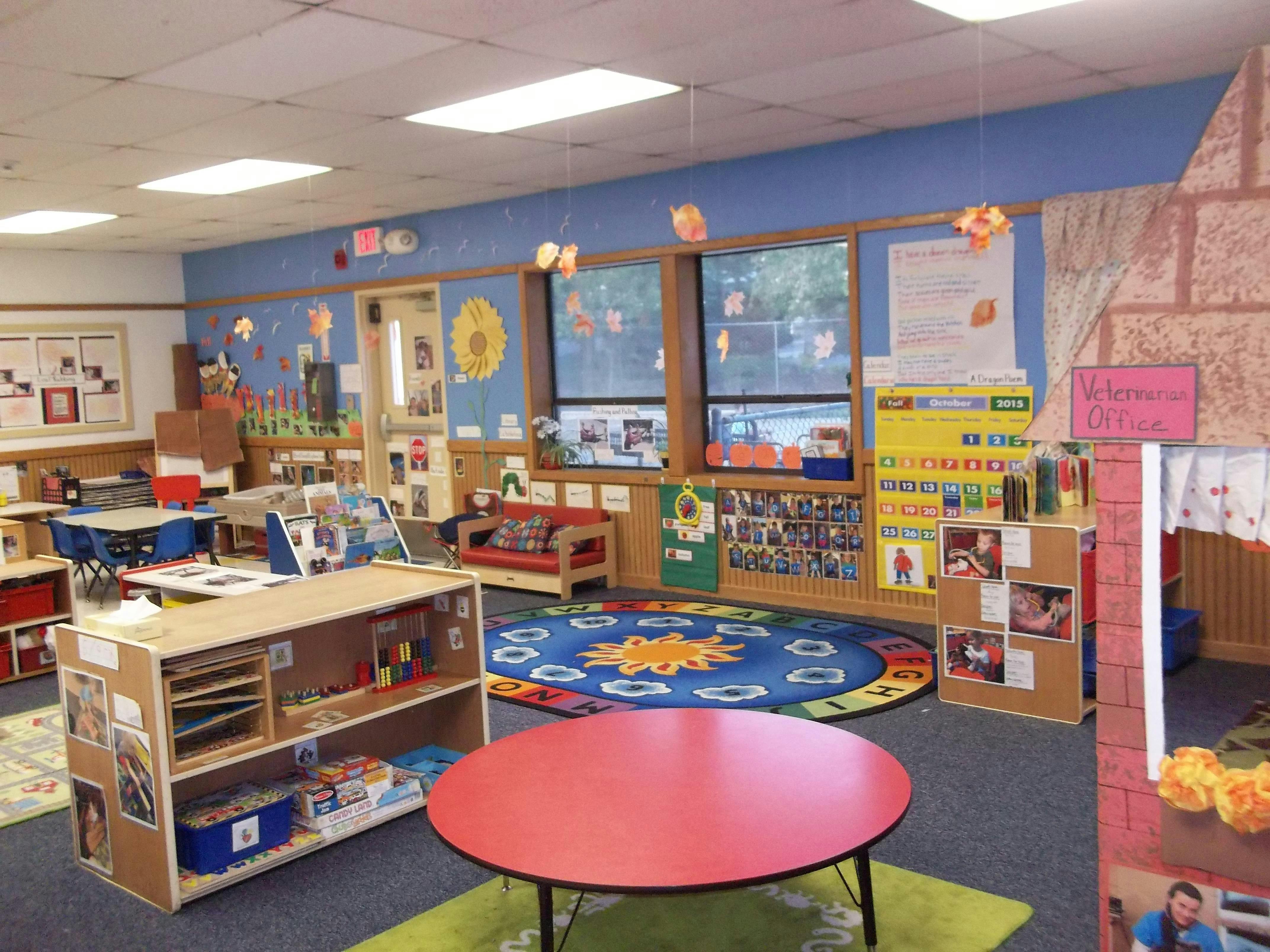 Classroom with tables, shelves, a rug with letters, and fall decorations