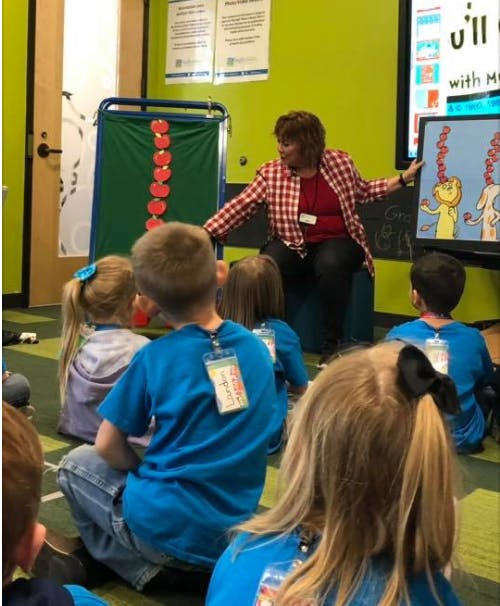 Adult person reading to children in a classroom