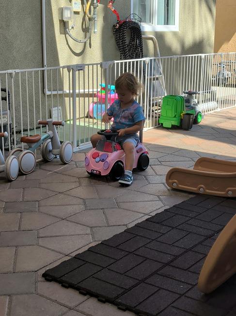 Child sitting on a toy car outdoors