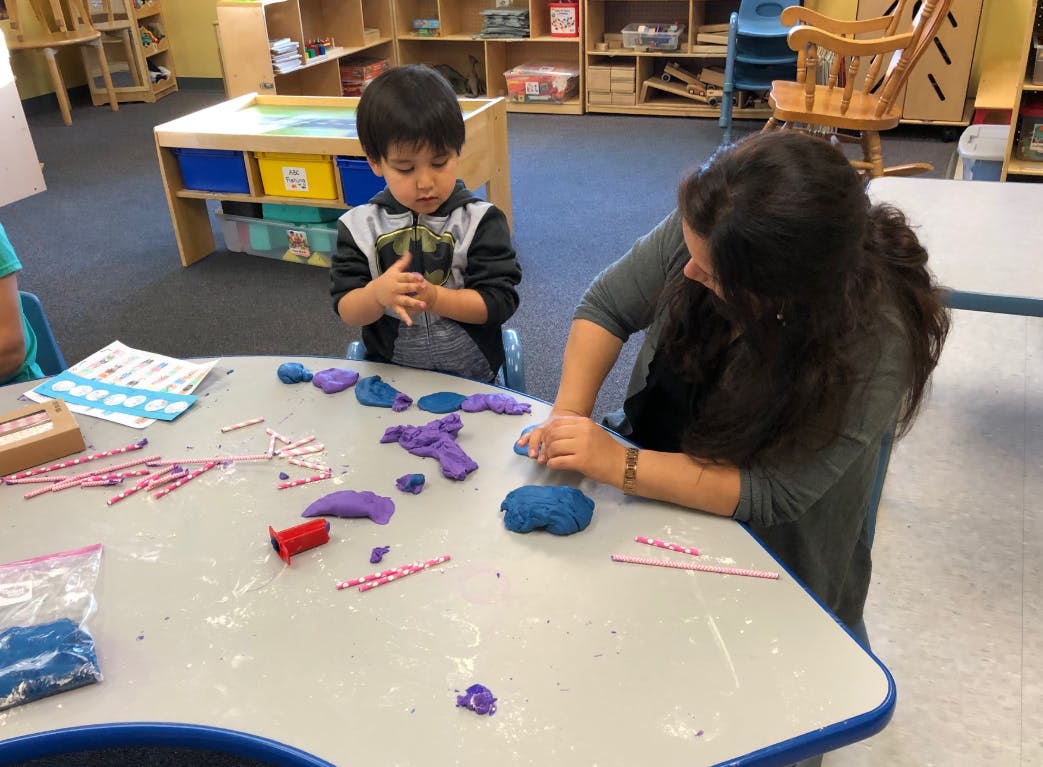 Person and child playing with modeling clay at a table