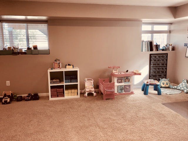 Playroom with toys, shelves, and windows