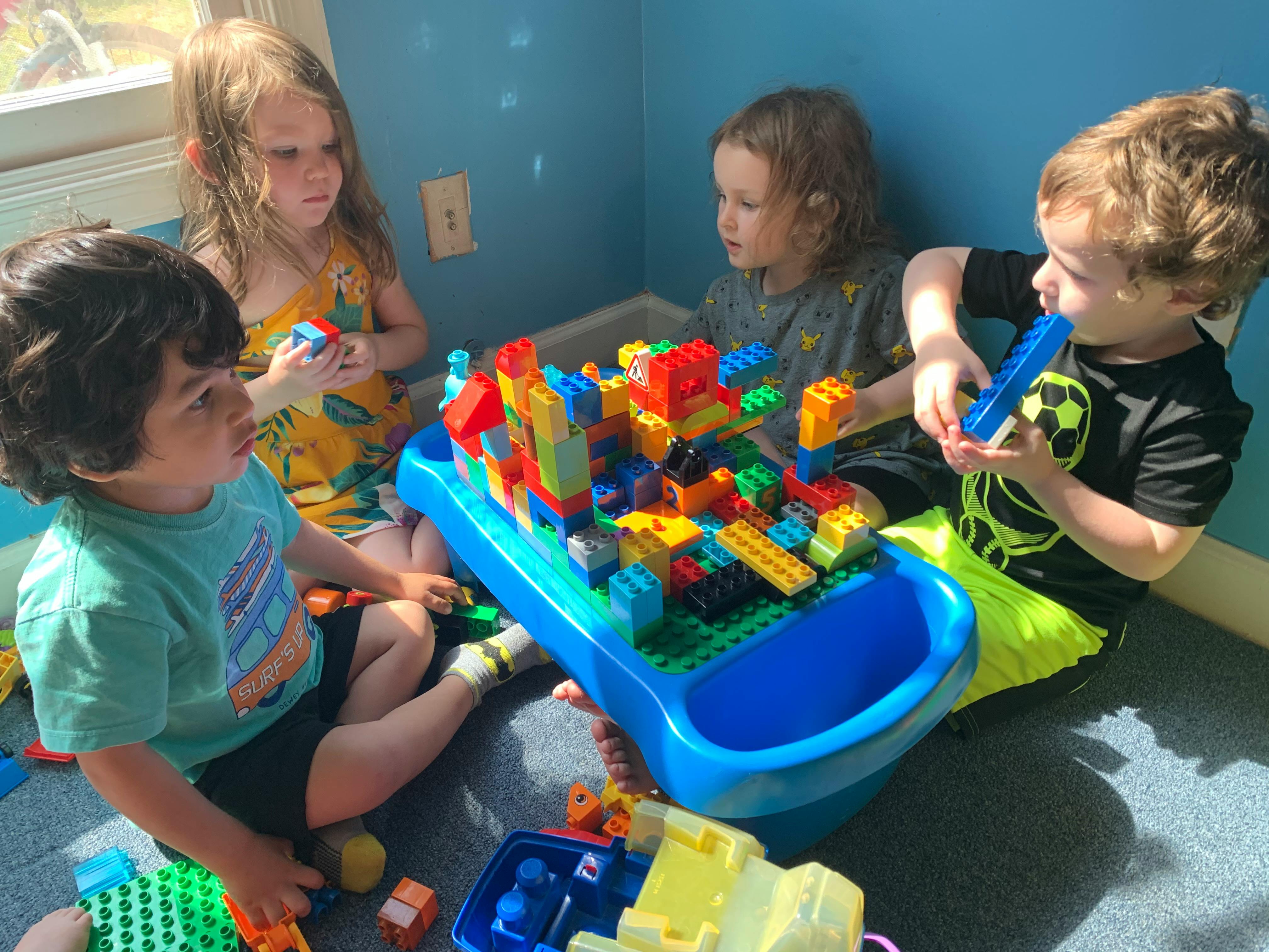 Four children playing with building blocks on the floor
