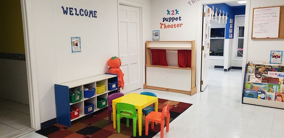 Children's play area with a puppet theater, small table and chairs, and toy storage