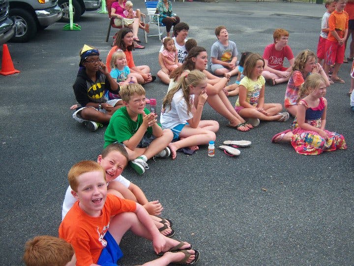 Group of children and teens sitting on asphalt