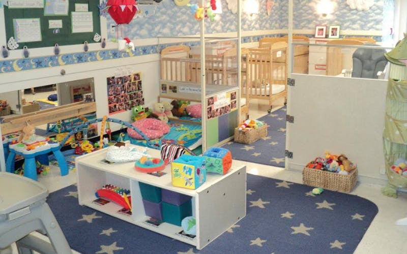 cribs and play area with toys in a childcare room