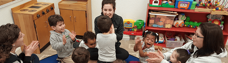 Adults and children sitting in a circle, some clapping