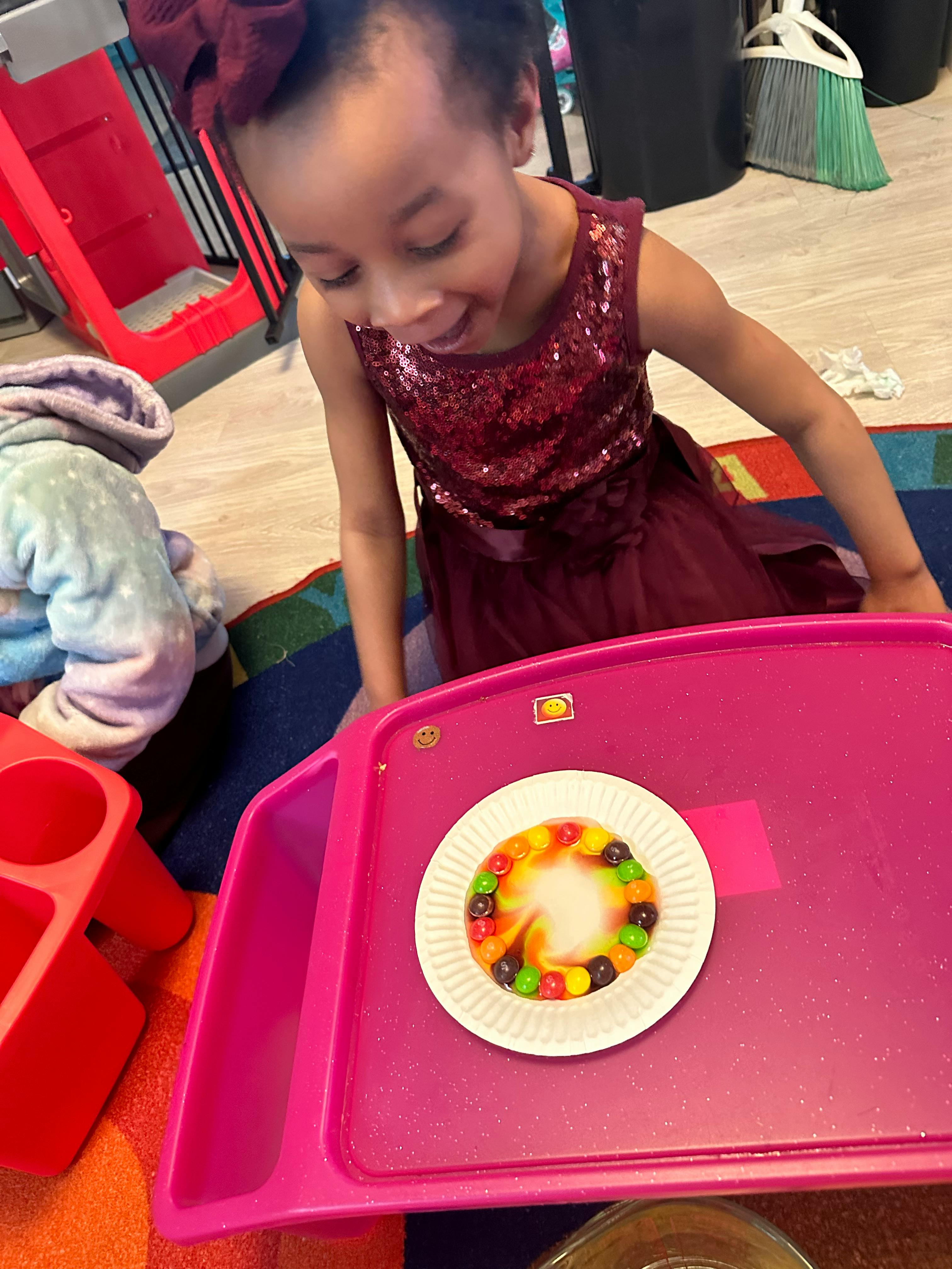 Child looking at a plate of colorful candies on a pink tray