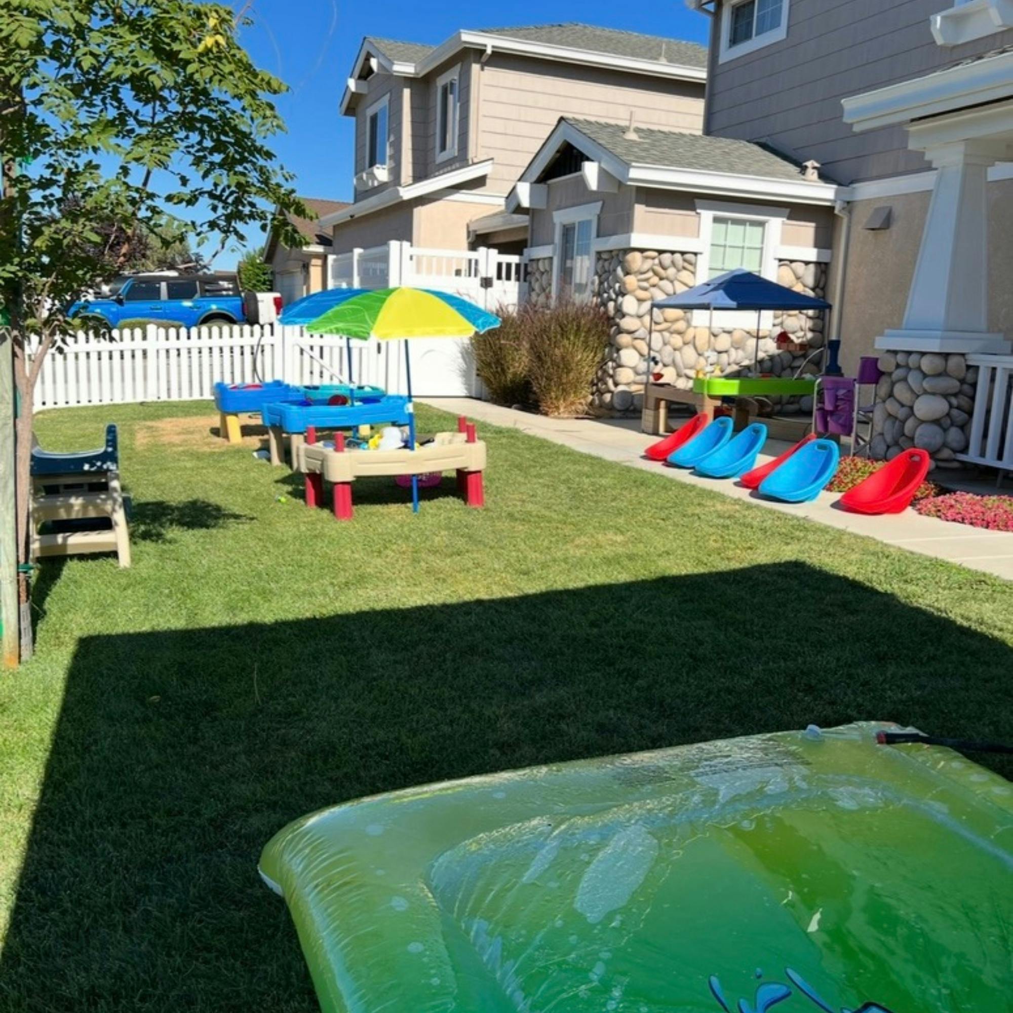 Backyard with green grass and various outdoor children's toys and furniture