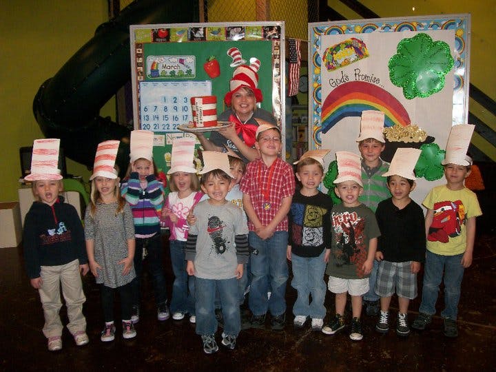 Adult and children wearing striped hats standing in front of classroom decorations