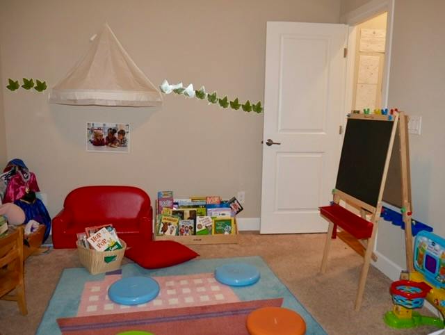 Playroom with a small sofa, books, and a standing chalkboard