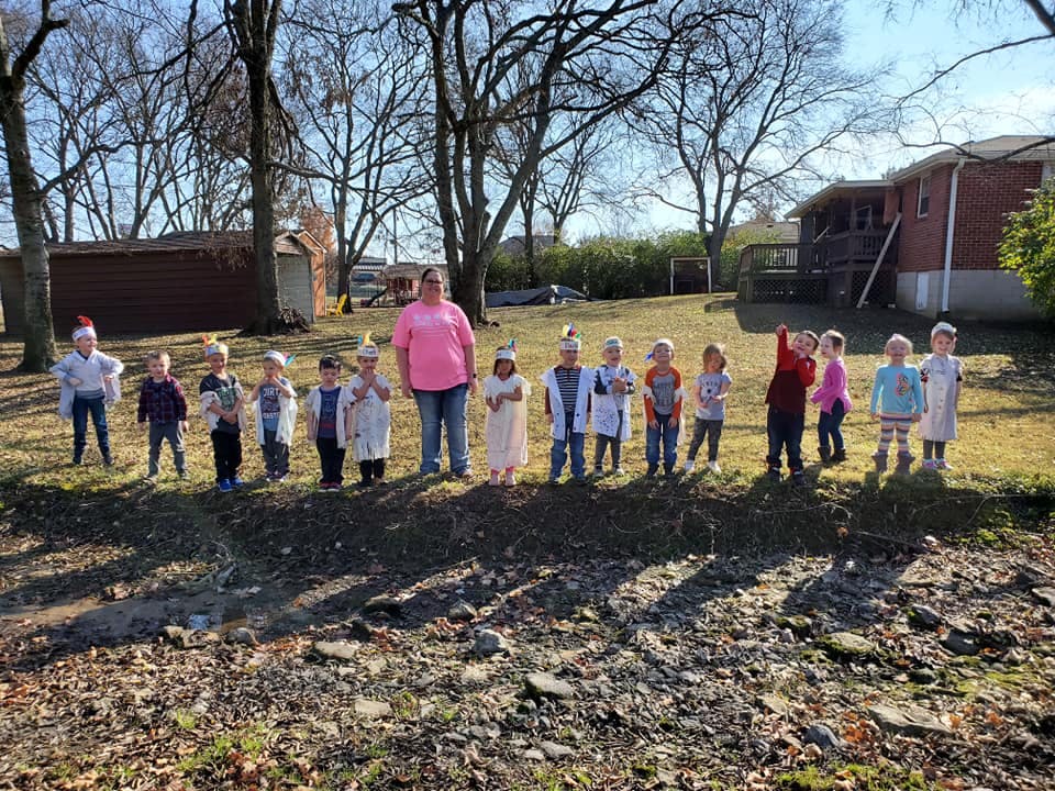 Adult and multiple children standing in a line outdoors