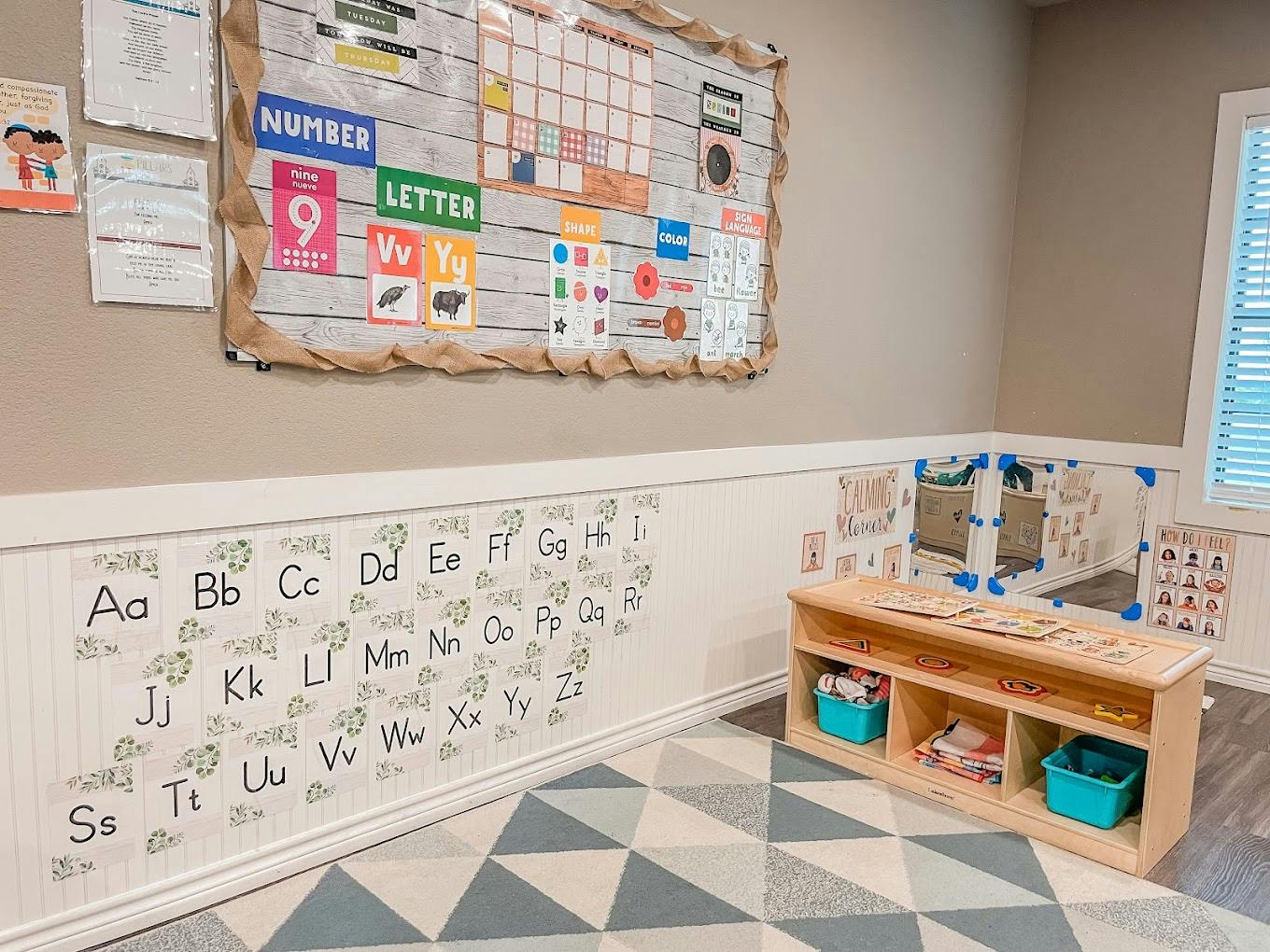 Classroom wall with alphabet letters, a calendar, and a shelving unit