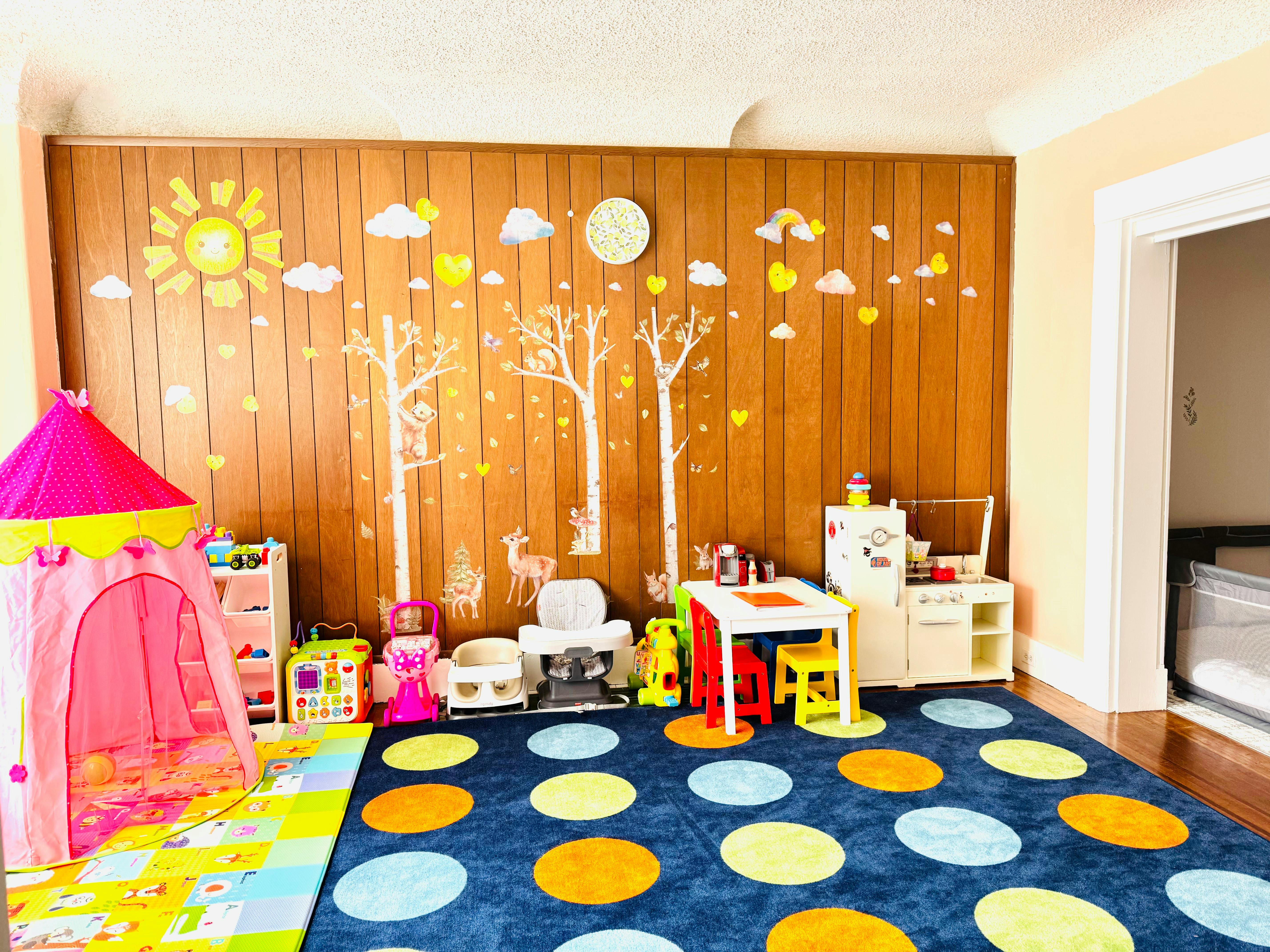 Playroom with a pink tent, small table and chairs, and a blue polka dot rug