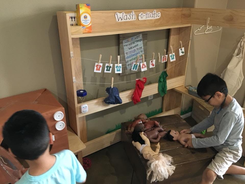 Two children playing with dolls and a clothesline with small clothes