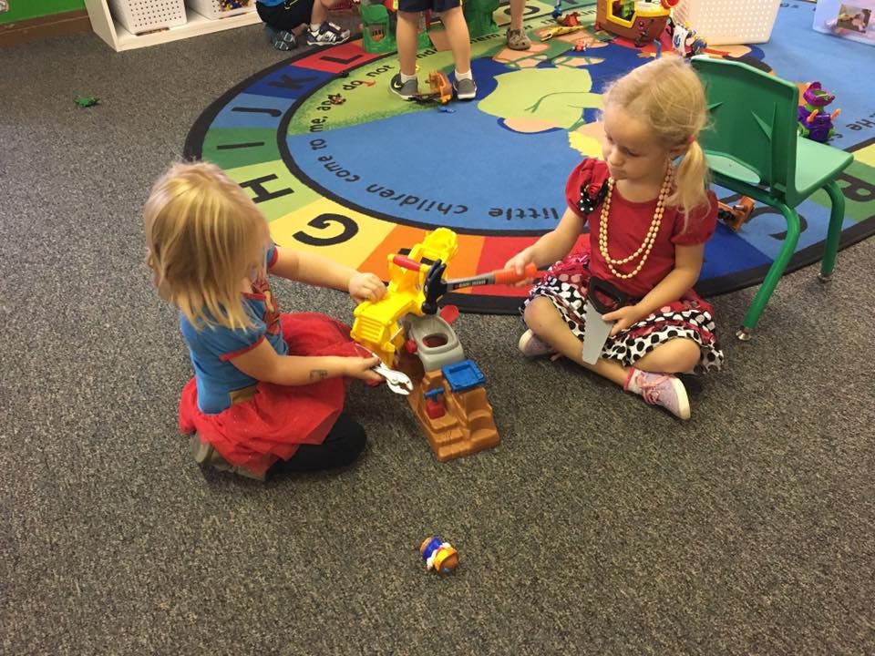 Two children playing with a toy construction set on a rug