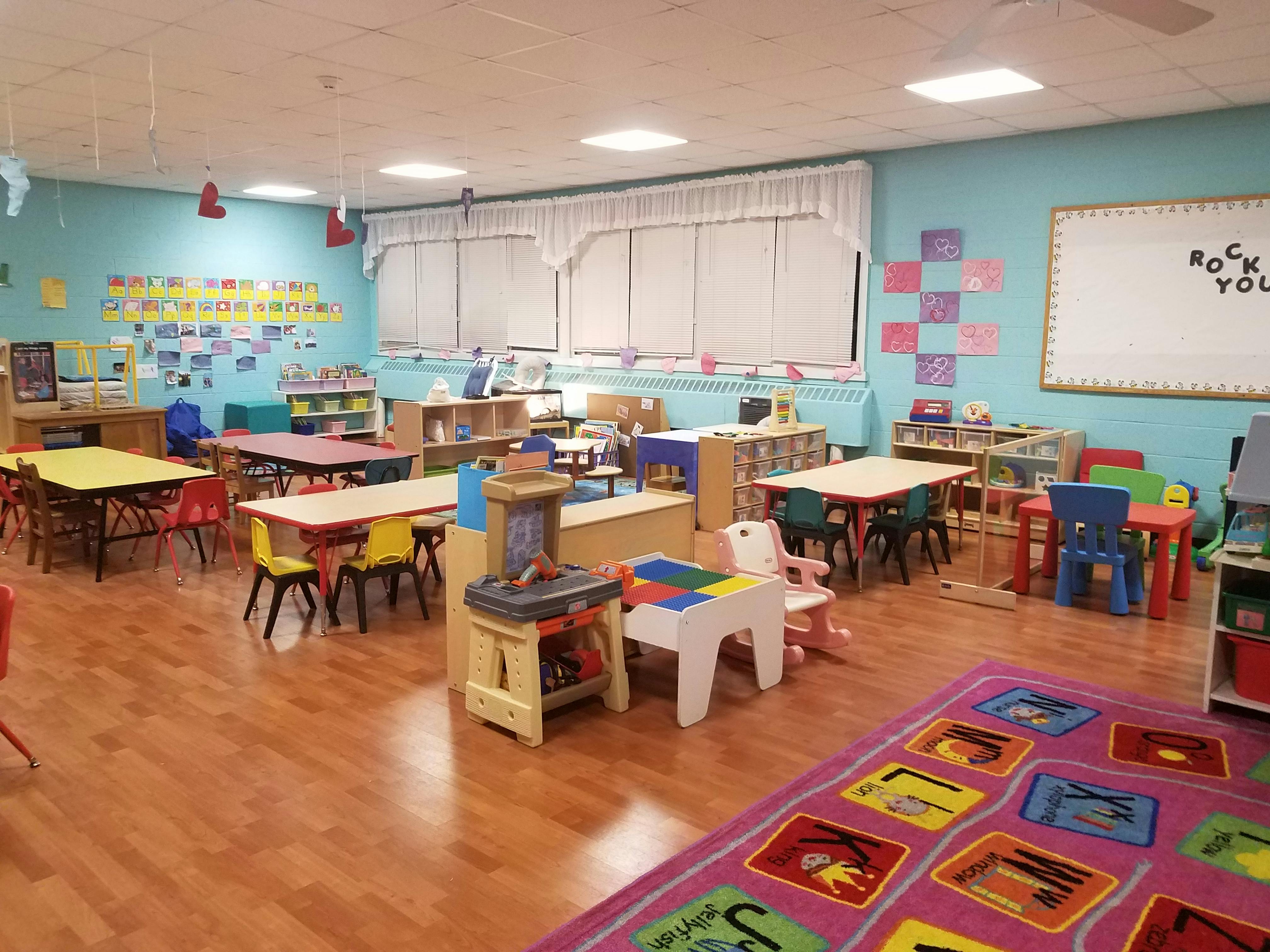 Classroom with small tables and chairs, toys, and a whiteboard