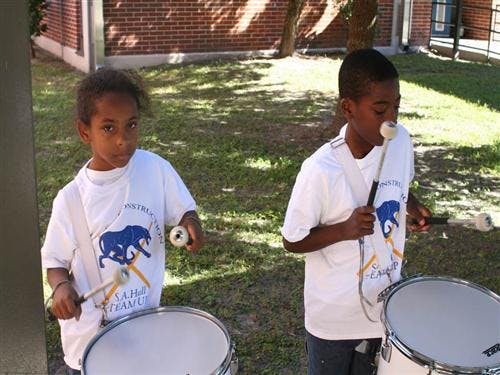 Two children playing drums outdoors