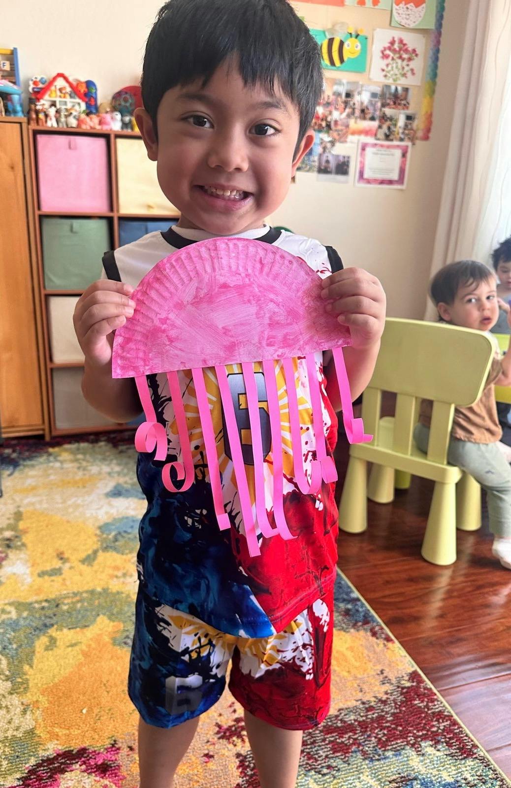 Child holding a paper plate jellyfish craft
