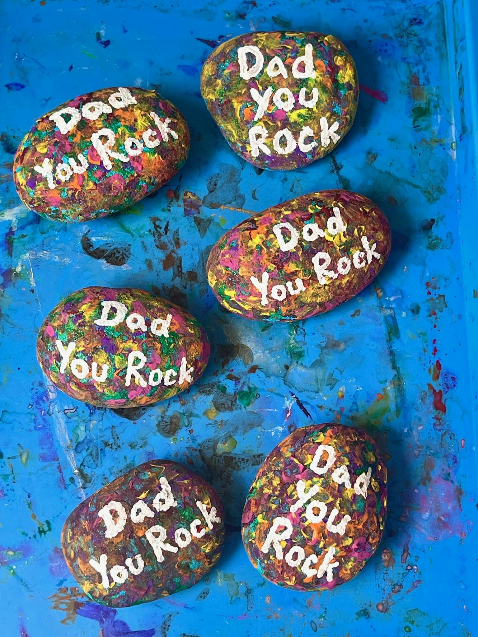 Five colorful painted rocks with the phrase Dad you rock written on each