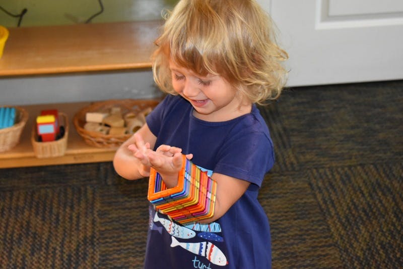 Child looking at colorful magnetic tiles on their arm
