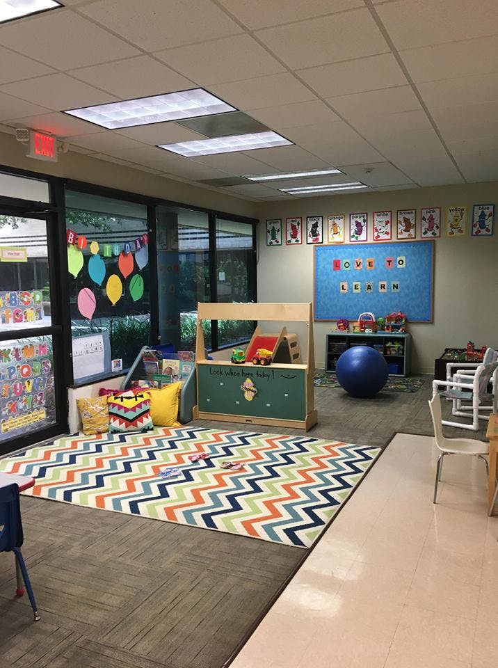 Classroom with a colorful rug, play structure, and bulletin board that says "Love to Learn"