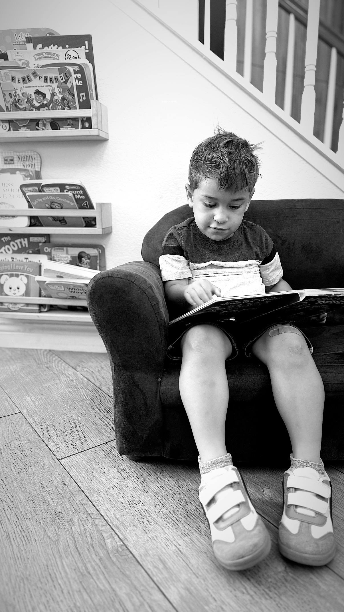 Child sitting on a couch reading a book