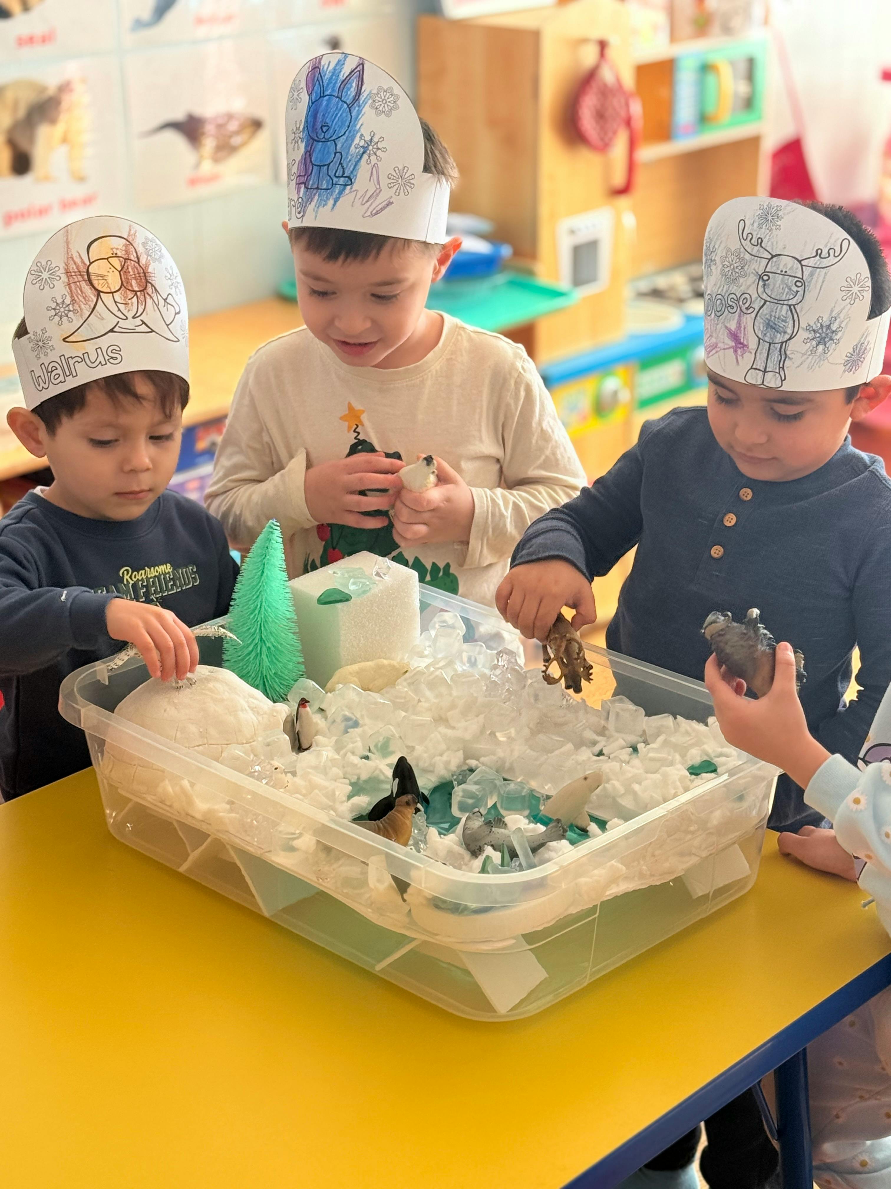 Three children playing with a sensory bin filled with white material and blue materials
